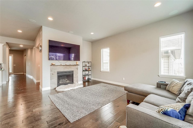 living area with dark wood-style floors, recessed lighting, baseboards, and a glass covered fireplace