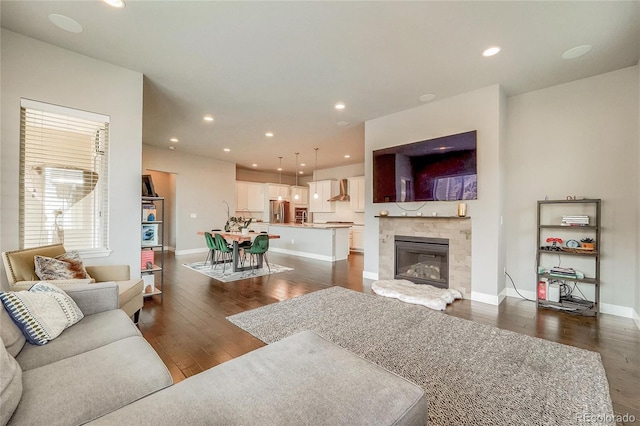 living area with baseboards, dark wood-type flooring, a tile fireplace, and recessed lighting