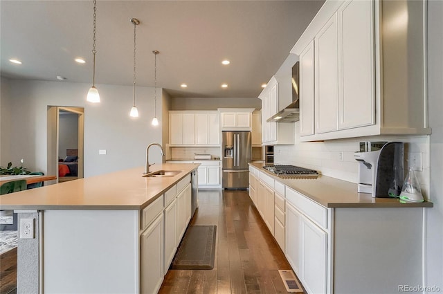 kitchen with tasteful backsplash, dark wood finished floors, appliances with stainless steel finishes, wall chimney range hood, and a sink