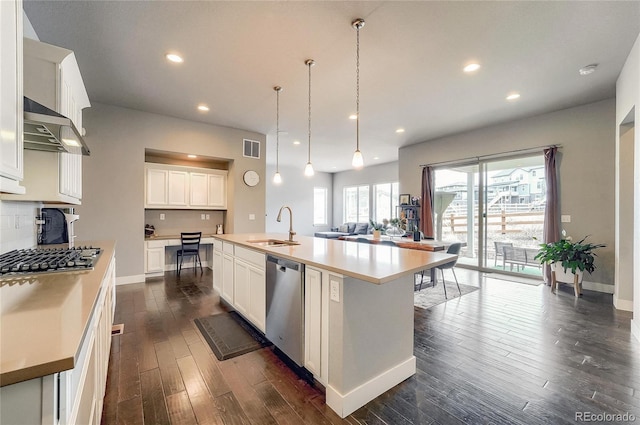 kitchen with visible vents, dark wood-style floors, range hood, stainless steel appliances, and a sink