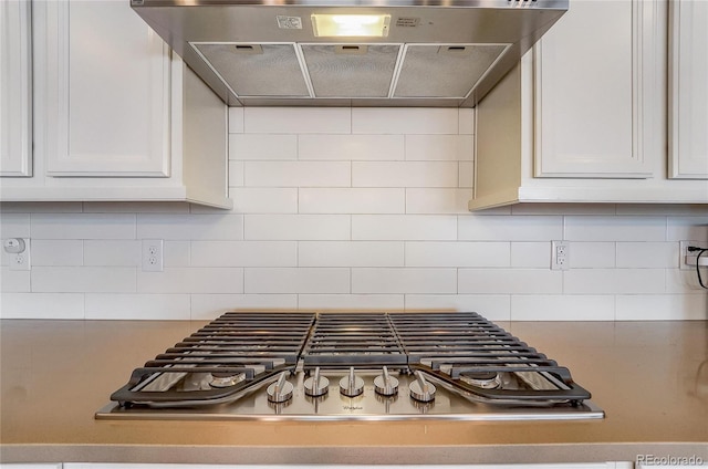 room details with stainless steel gas cooktop, tasteful backsplash, white cabinetry, and under cabinet range hood