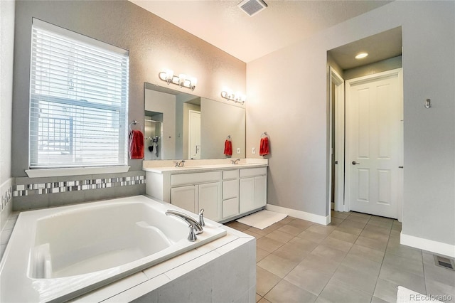 bathroom featuring a garden tub, tile patterned flooring, a sink, visible vents, and double vanity