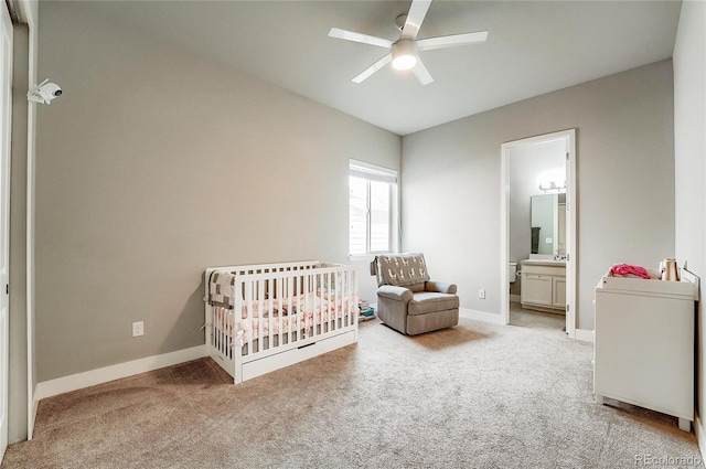 carpeted bedroom featuring a nursery area, ceiling fan, baseboards, and a sink