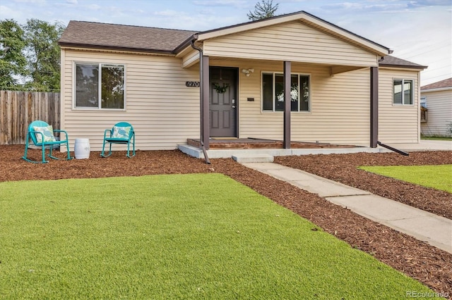 single story home with a shingled roof, a front lawn, and fence