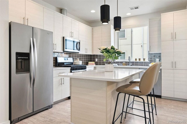 kitchen featuring light wood-style floors, stainless steel appliances, a kitchen breakfast bar, and visible vents