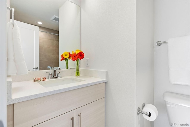 bathroom with toilet, visible vents, vanity, and recessed lighting