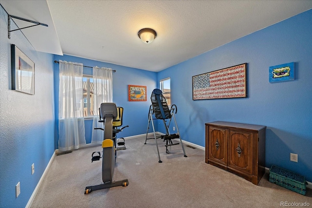 workout room with light colored carpet and a textured ceiling