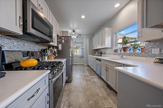 kitchen featuring sink, white cabinets, ceiling fan, light hardwood / wood-style floors, and stainless steel appliances