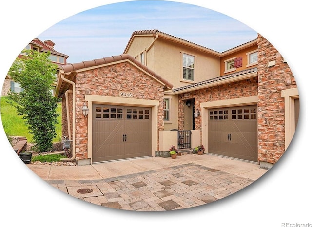 9246 Sori Ln, Highlands Ranch, CO 80126 - view of front of home featuring stone siding, stucco siding, a tiled roof, driveway, and a garage