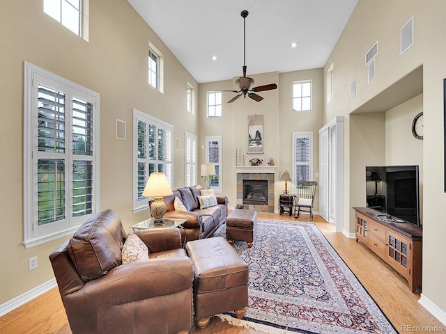 9246 Sori Ln, Highlands Ranch, CO 80126 - living area with a towering ceiling, ceiling fan, a tile fireplace, healthy amount of natural light, and light wood-style floors