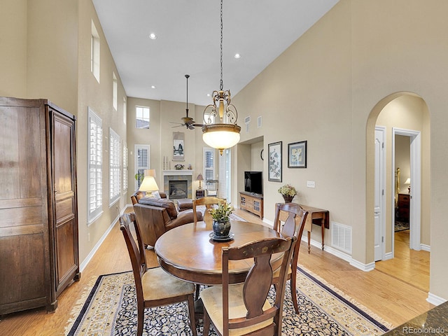 9246 Sori Ln, Highlands Ranch, CO 80126 - dining area with a ceiling fan, a towering ceiling, light wood finished floors, arched walkways, and a tiled fireplace