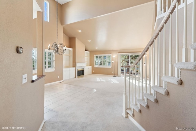 unfurnished living room with a high ceiling, light carpet, and a notable chandelier