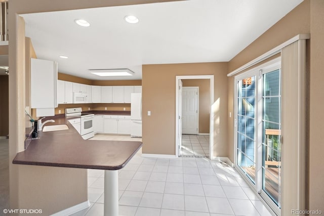 kitchen with sink, a breakfast bar area, kitchen peninsula, white appliances, and white cabinets