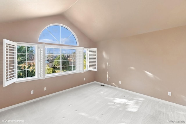 carpeted spare room featuring high vaulted ceiling