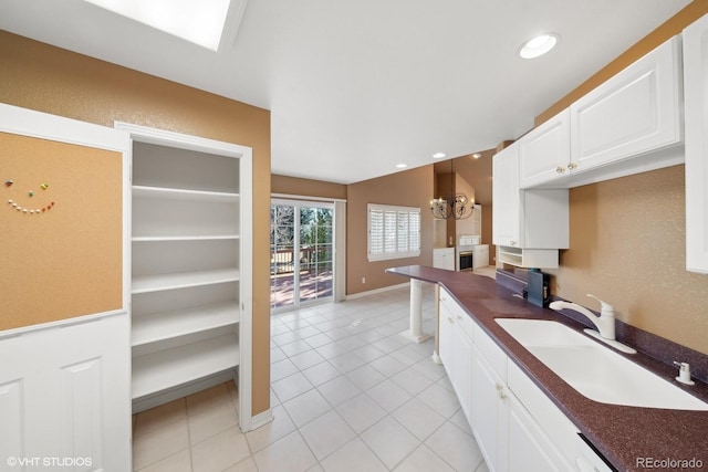 kitchen featuring sink, light tile patterned floors, and white cabinets