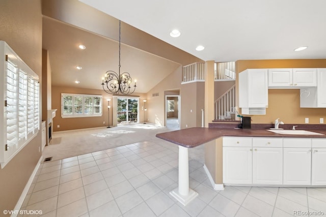 kitchen featuring pendant lighting, sink, a breakfast bar area, white cabinets, and light colored carpet