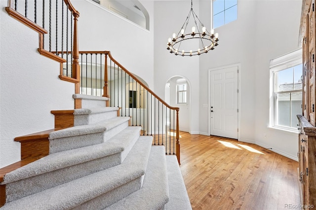 2832 Danbury Ave, Highlands Ranch, CO 80126 - foyer entrance with stairway, light wood finished floors, arched walkways, a chandelier, and a towering ceiling
