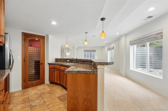 2832 Danbury Ave, Highlands Ranch, CO 80126 - kitchen with brown cabinets, a peninsula, a sink, hanging light fixtures, and recessed lighting