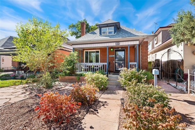 511 S Pennsylvania St, Denver, CO 80209 - bungalow with brick siding, a porch, roof with shingles, and a chimney