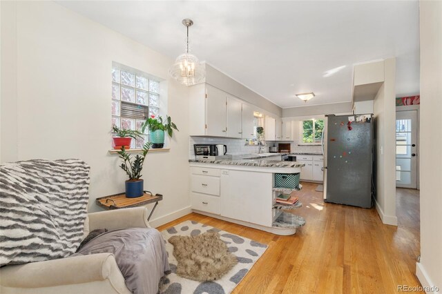 511 S Pennsylvania St, Denver, CO 80209 - kitchen featuring freestanding refrigerator, white cabinetry, light wood finished floors, light countertops, and tasteful backsplash