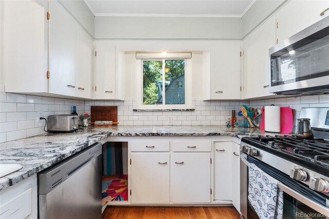511 S Pennsylvania St, Denver, CO 80209 - kitchen with stainless steel appliances, ornamental molding, white cabinets, light wood-style floors, and backsplash