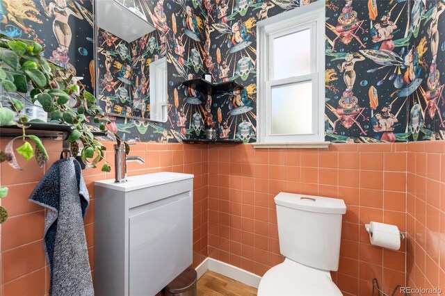 511 S Pennsylvania St, Denver, CO 80209 - half bath featuring wallpapered walls, tile walls, vanity, toilet, and a wainscoted wall