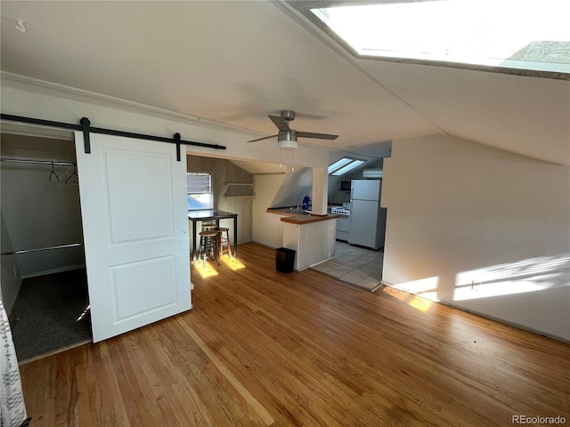 511 S Pennsylvania St, Denver, CO 80209 - unfurnished living room with ceiling fan, light wood-style flooring, a barn door, and vaulted ceiling