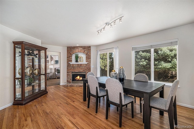 8825 Fairview Oaks Pl, Lone Tree, CO 80124 - dining area featuring a brick fireplace, light wood-type flooring, and track lighting