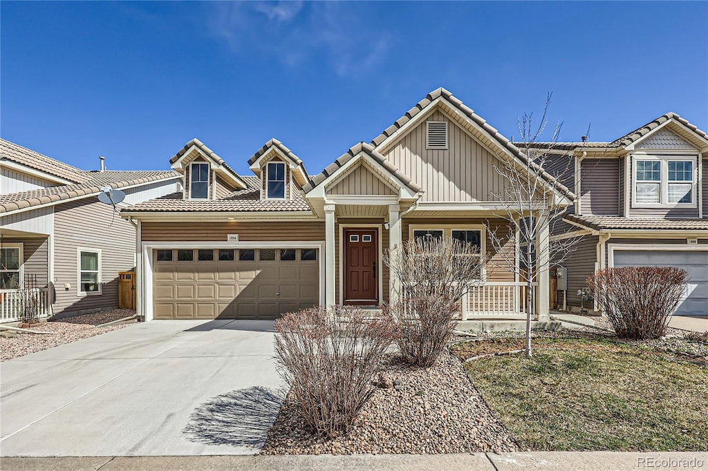 view of front of home featuring driveway, a tile roof, a porch, board and batten siding, and an attached garage