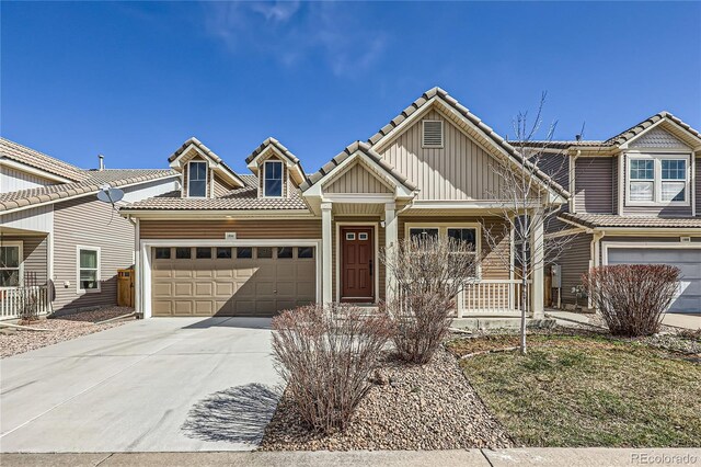 view of front of home featuring driveway, a tile roof, a porch, board and batten siding, and an attached garage