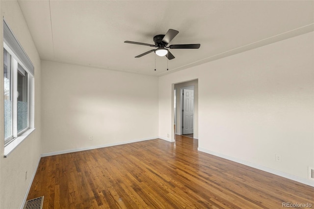 empty room with baseboards, visible vents, wood finished floors, and a ceiling fan