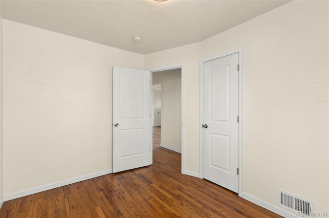 unfurnished bedroom featuring wood finished floors, baseboards, and visible vents