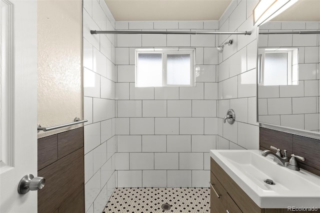 full bath with tile walls, tiled shower, and vanity