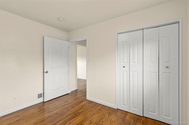 unfurnished bedroom with baseboards, wood finished floors, and a closet