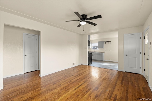 unfurnished living room featuring baseboards, wood finished floors, and a ceiling fan