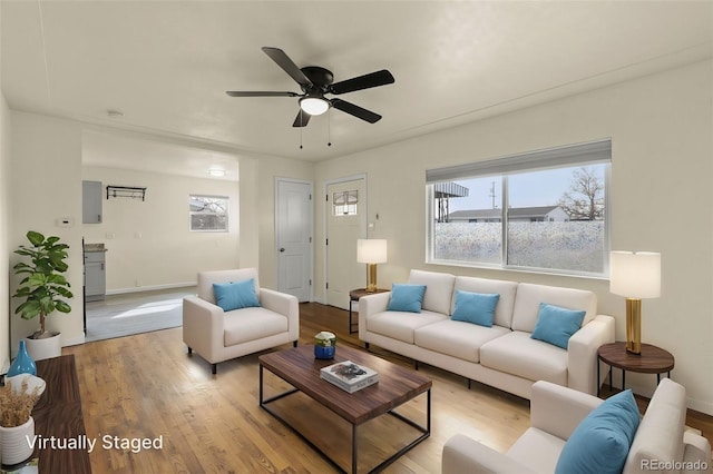 living room featuring a ceiling fan, baseboards, and wood finished floors