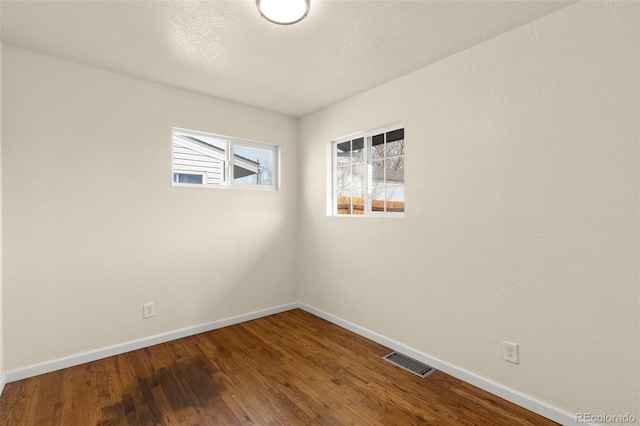unfurnished room with baseboards, visible vents, and wood finished floors
