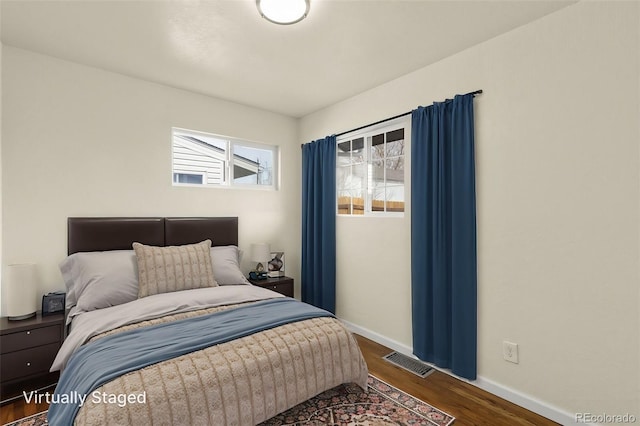 bedroom featuring baseboards, visible vents, and wood finished floors