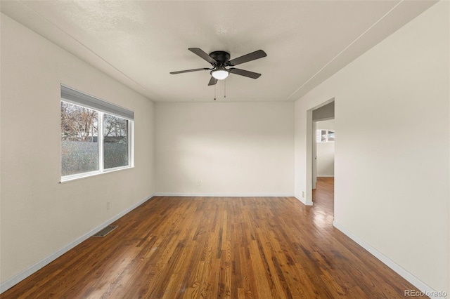 empty room with baseboards, visible vents, wood finished floors, and a ceiling fan