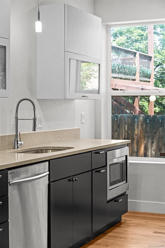 1211 E 26th Ave, Denver, CO 80205 - kitchen featuring stainless steel appliances, a sink, light wood-style floors, healthy amount of natural light, and a textured wall