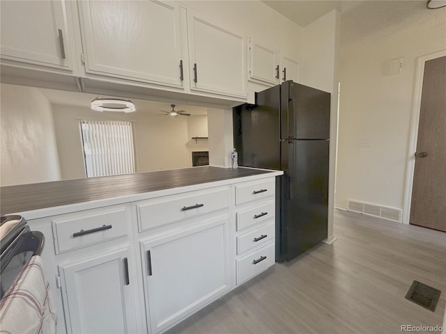 56 S Nome St, Aurora, CO 80012 - kitchen with freestanding refrigerator, range, light wood finished floors, white cabinets, and ceiling fan