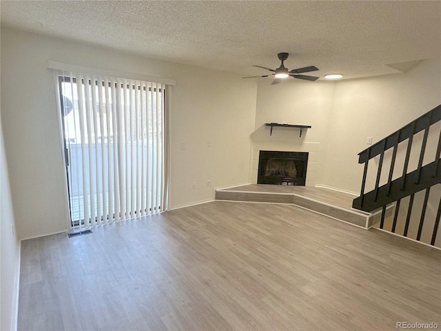 56 S Nome St, Aurora, CO 80012 - unfurnished living room featuring wood finished floors, ceiling fan, stairway, a fireplace, and a textured ceiling