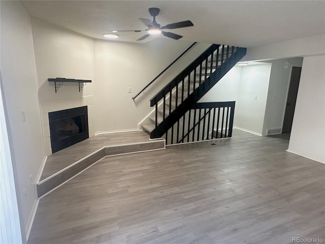 56 S Nome St, Aurora, CO 80012 - unfurnished living room featuring ceiling fan, a tile fireplace, wood finished floors, and stairs