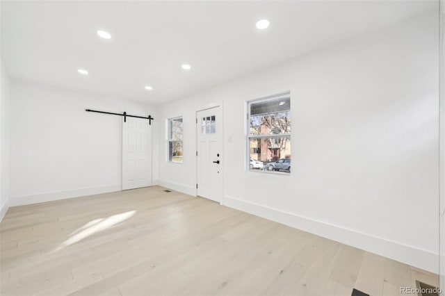 foyer entrance with light hardwood / wood-style floors and a barn door