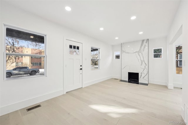 entrance foyer with plenty of natural light, a fireplace, and light hardwood / wood-style floors