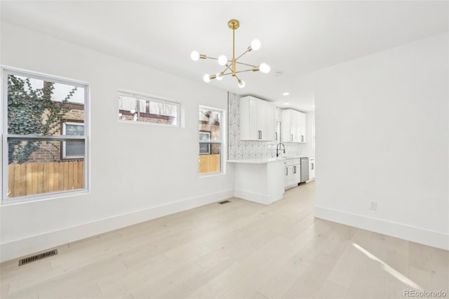 unfurnished room with an inviting chandelier and light hardwood / wood-style floors