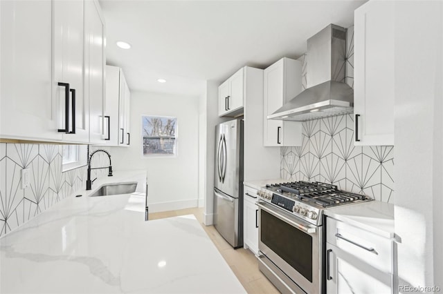 kitchen featuring stainless steel appliances, light stone countertops, sink, and wall chimney range hood