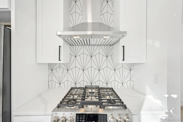 interior details featuring light stone counters, backsplash, white cabinetry, and ventilation hood