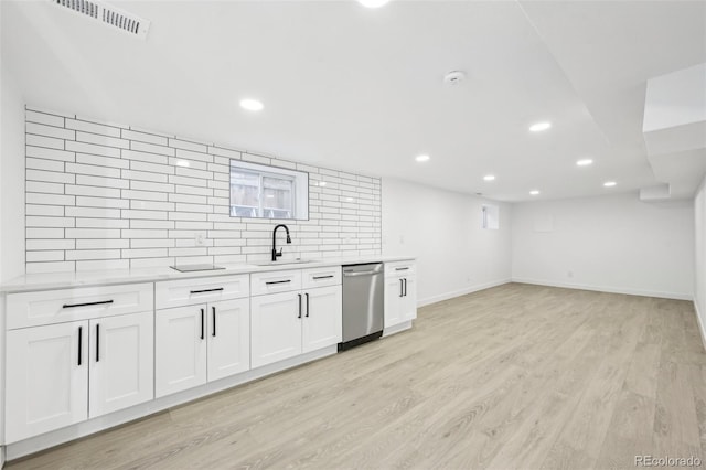 kitchen with tasteful backsplash, sink, white cabinets, stainless steel dishwasher, and light hardwood / wood-style floors