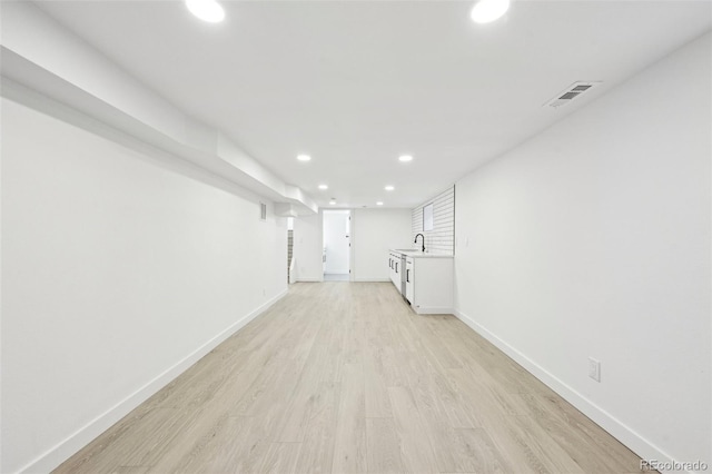 basement featuring sink and light hardwood / wood-style floors